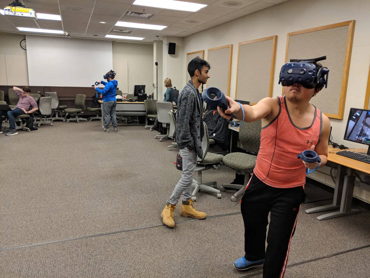 Participants use VR headsets and handheld controllers in a computer lab.